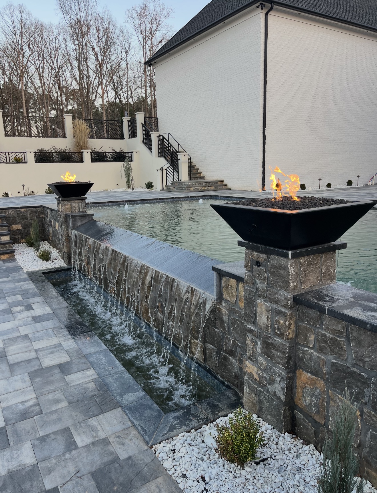 Geometric pool with sheer-descent waterfall and fire bowls